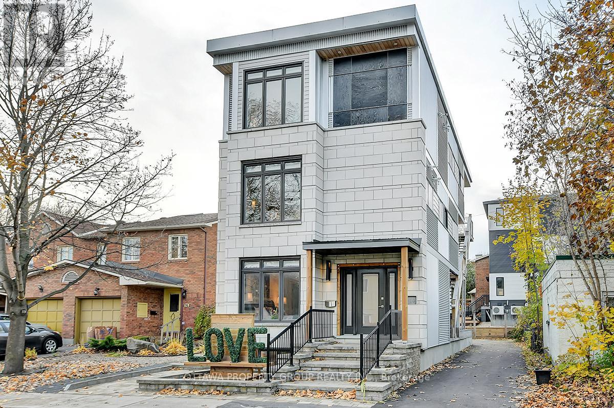A modern house with a grey facade and a black staircase.
