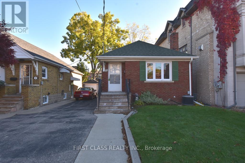 A red car is parked in front of a brick house.