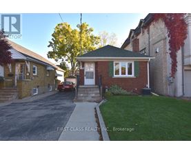 A red car is parked in front of a brick house.