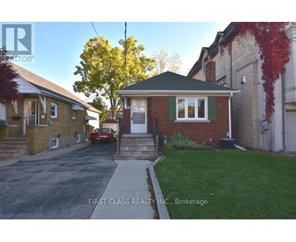 A red car is parked in front of a brick house.