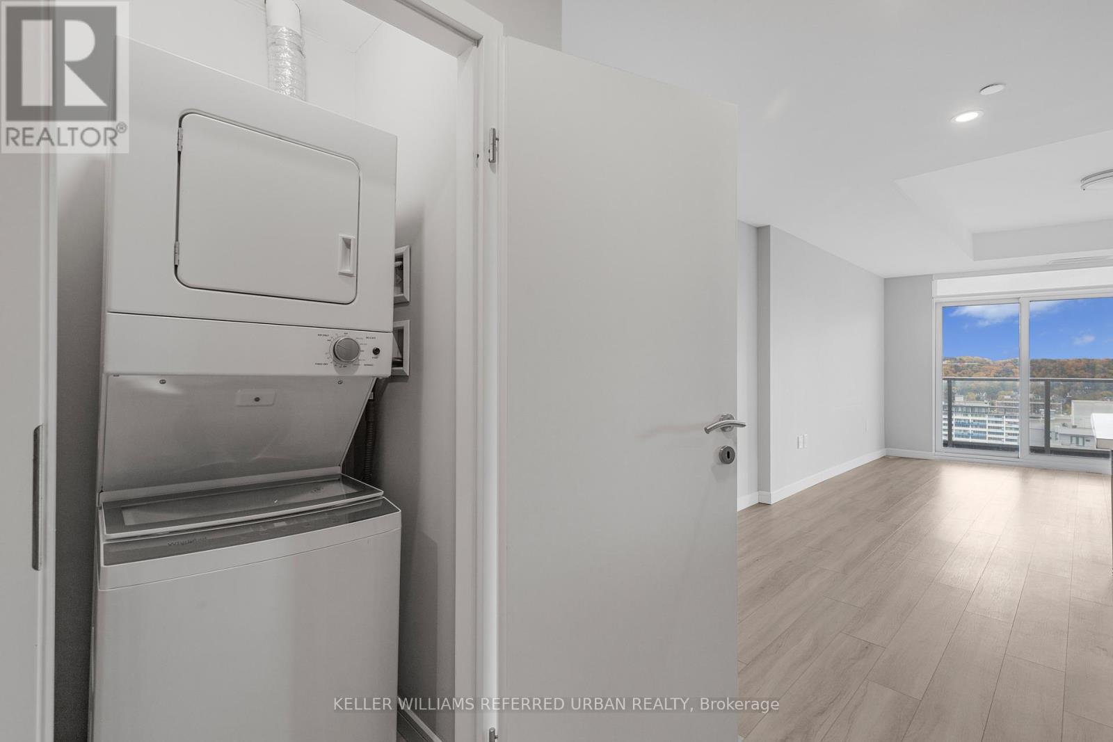 A kitchen with a refrigerator and a door open to a hallway.