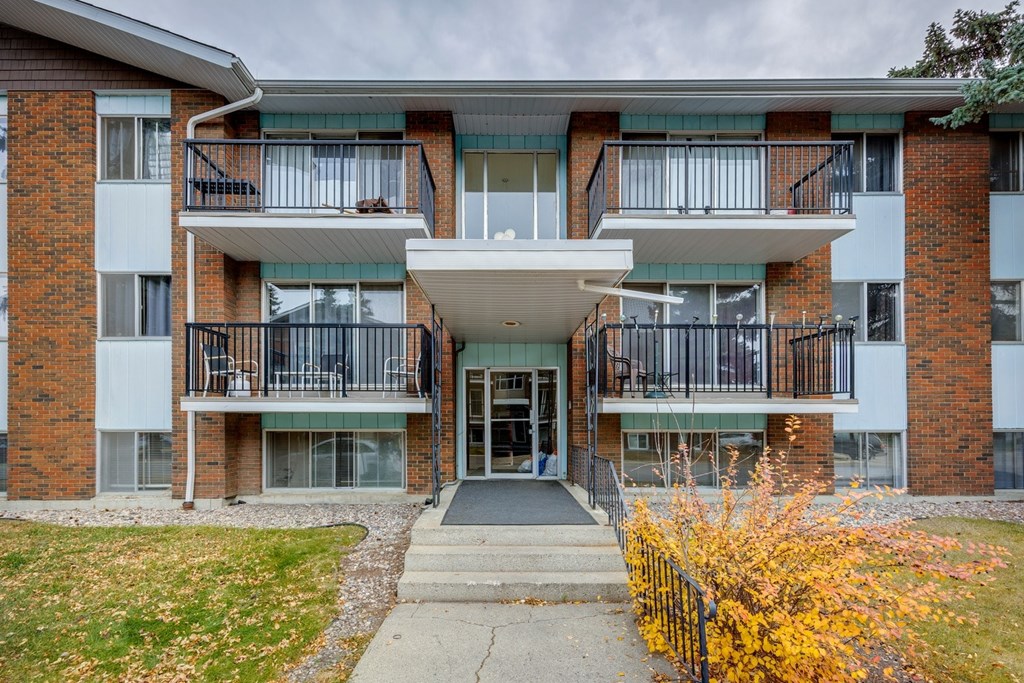 A brick building with a white overhang and a black fence in front.
