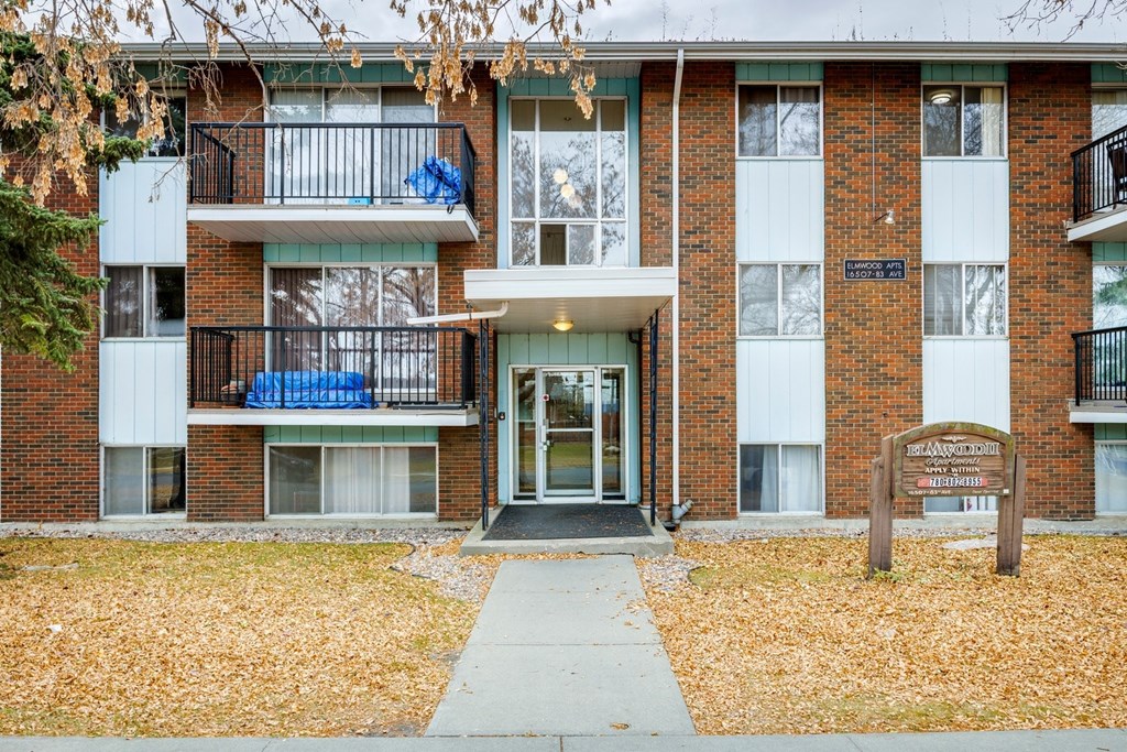 The image shows a brick building with a sign that reads "Sunset Hill Apartments."