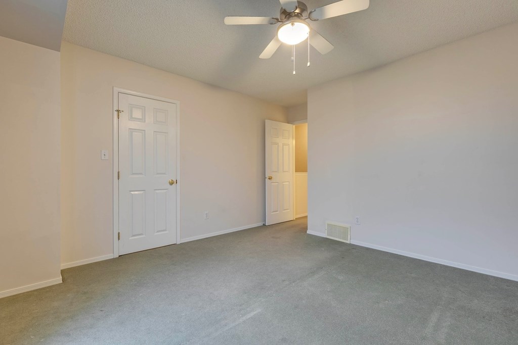 A room with a ceiling fan and two doors.