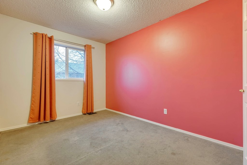 A room with orange walls and a window with orange curtains.