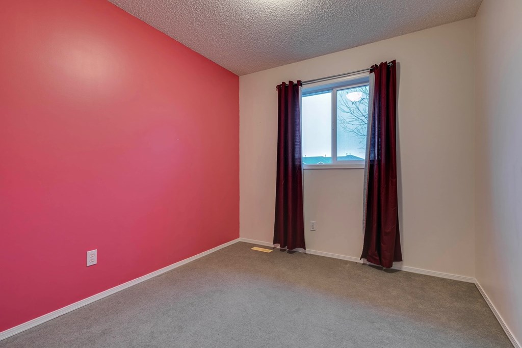 A room with red walls and a window with red curtains.