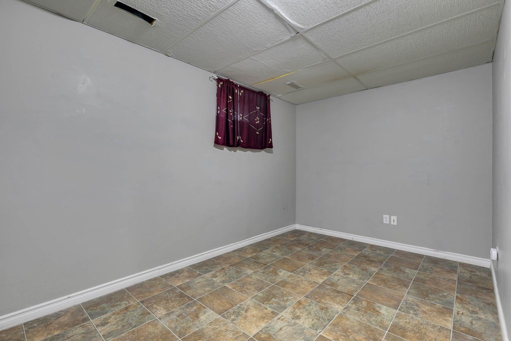 A room with a tiled floor and a window with a red curtain.
