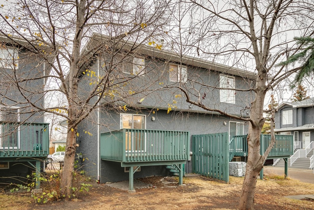 Apartment complex with green railings and trees in front.
