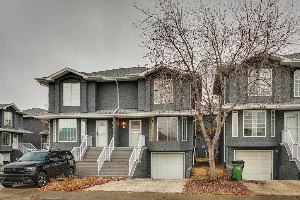 A black car is parked in front of a grey house.