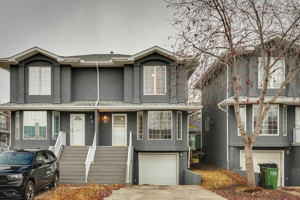 A grey house with a black car parked in front.