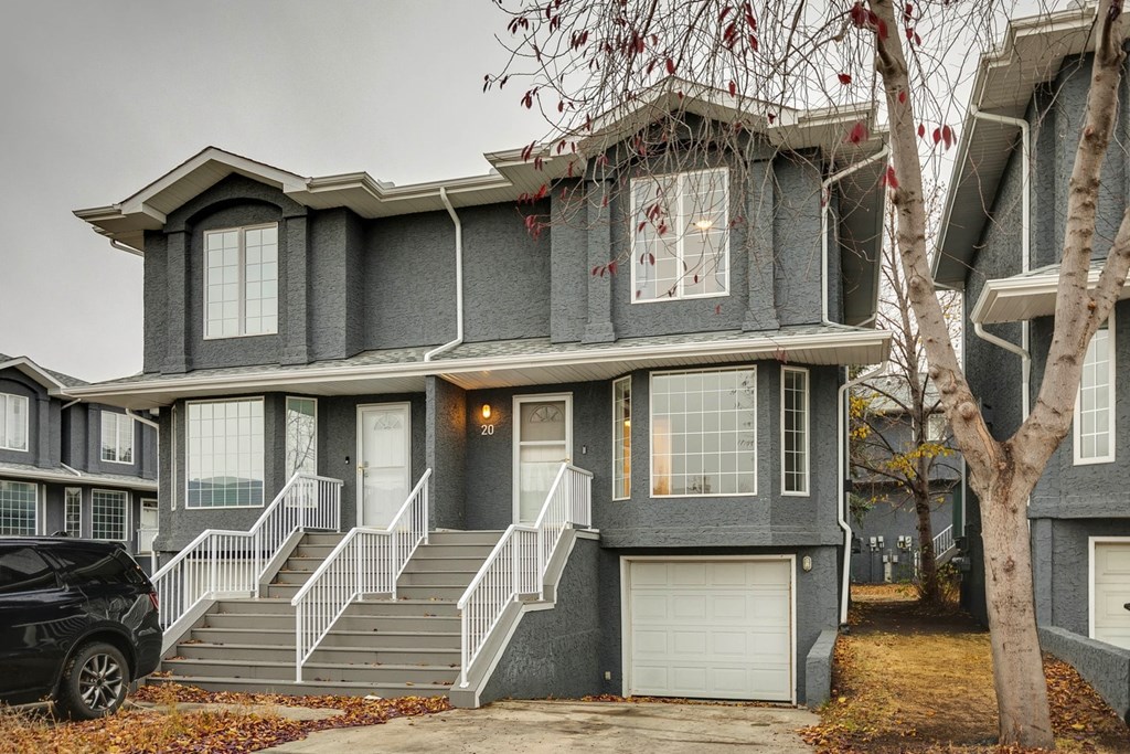 A grey two-story house with a black car parked in front.