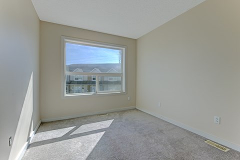 A room with a carpeted floor and a window overlooking a building.