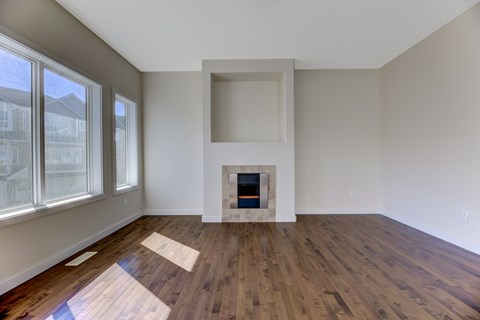 A room with a fireplace and wood flooring.