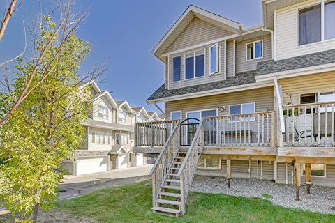 A house with a deck and a tree in front.