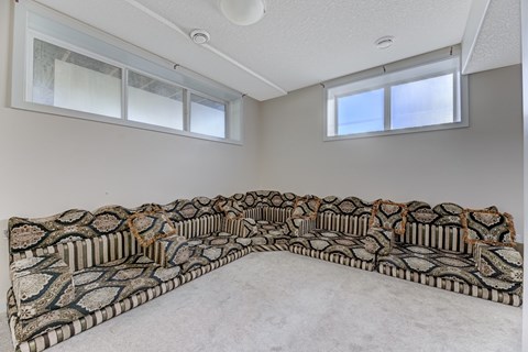 A large, patterned sofa sits in a room with two windows.