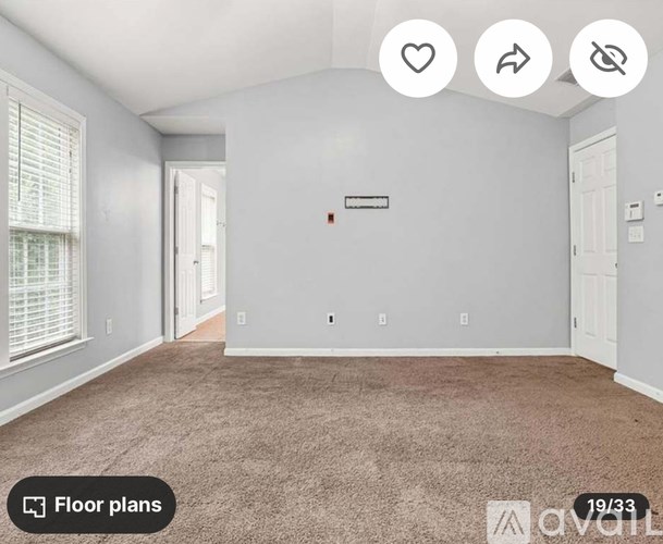 A room with a carpeted floor and a fireplace.