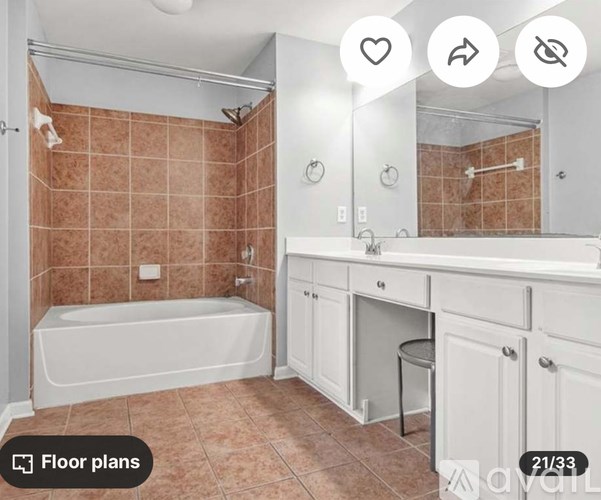 A bathroom with brown tiles and a white tub.