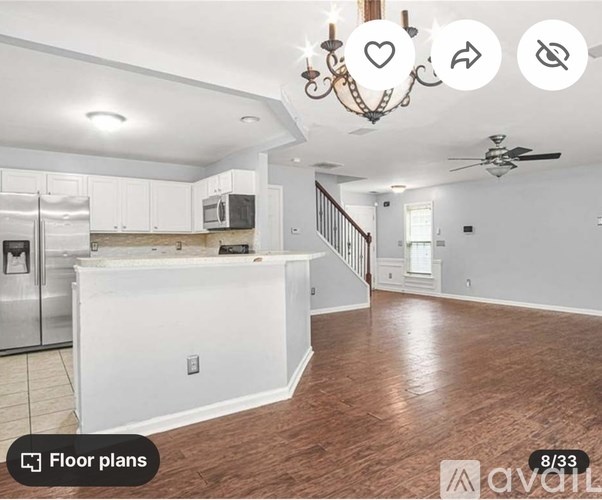 A spacious kitchen with white cabinets and a wooden floor.