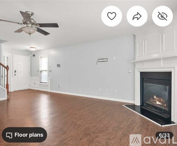 A spacious room with a fireplace and a ceiling fan.