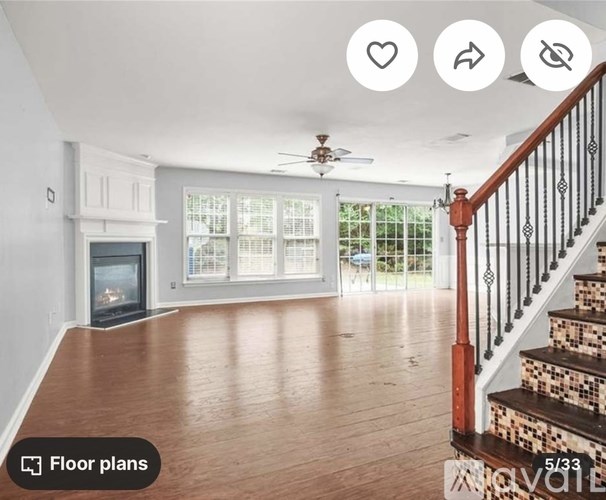A spacious living room with a fireplace and a staircase.