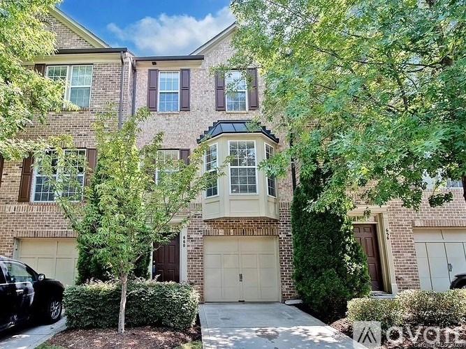 A row of houses with a black car parked in front of the first one.