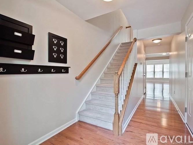 A staircase with a wooden handrail and white steps leads to a bright room.