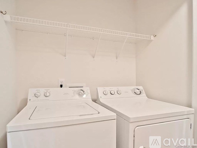 Two white front loading washing machines in a laundry room.