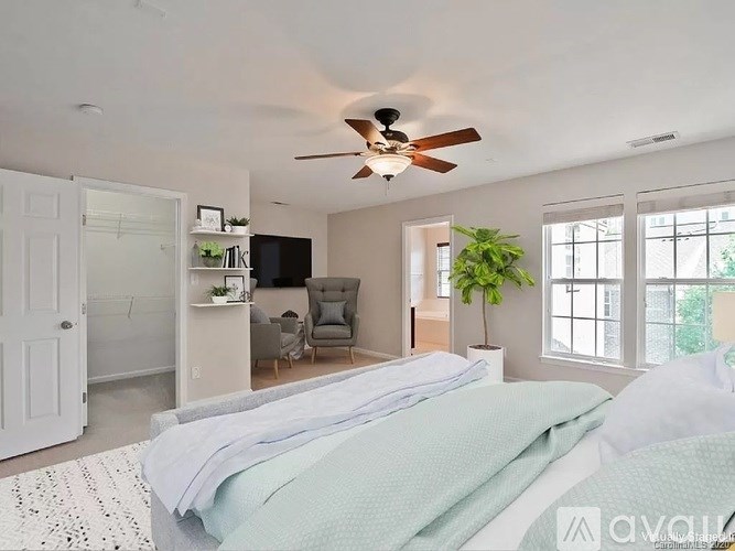A bedroom with a bed, a chair, and a ceiling fan.