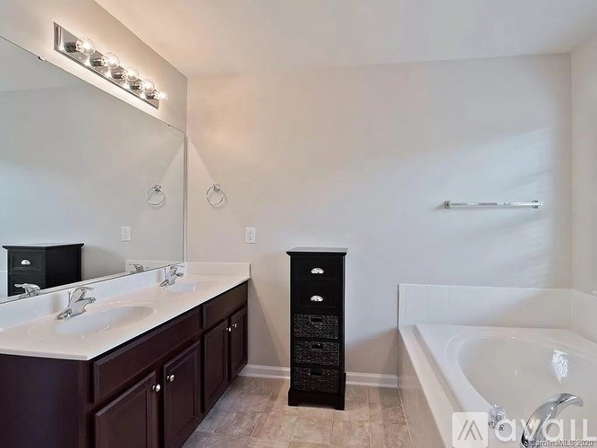A bathroom with a white tub, sink, and mirror.