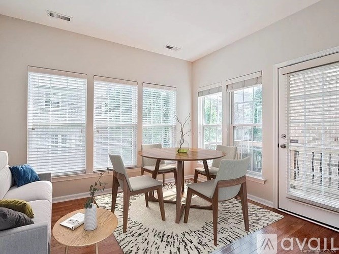 A dining room with a table set for four and a sofa with a throw pillow.