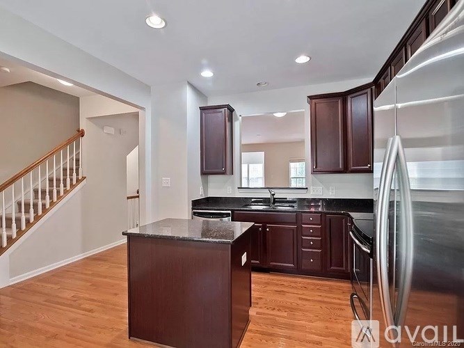 A kitchen with dark wood cabinets and a stainless steel refrigerator.