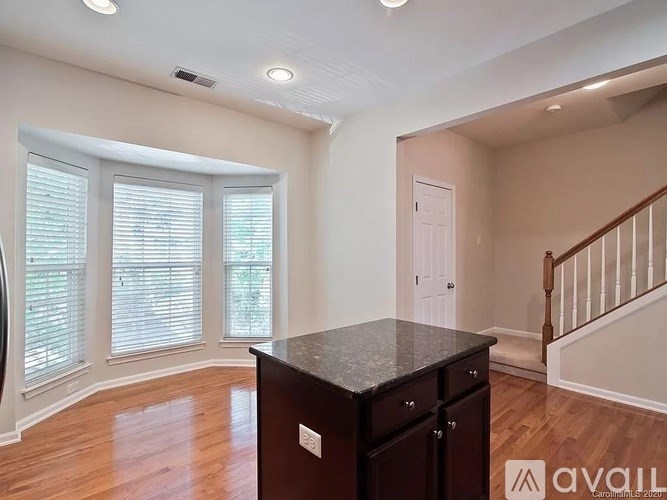 A kitchen with a dark countertop and wooden floors.
