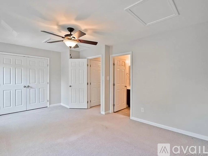A room with a ceiling fan and white walls.