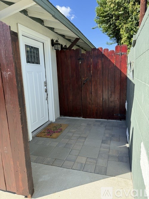 A white door is open to a small patio with a rug on the ground.