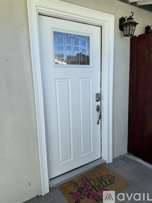 A white door with a glass window and a doormat with the word "Belle" on it.
