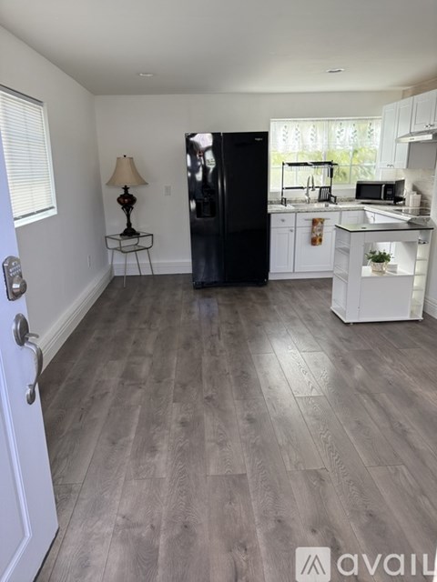 A kitchen with a black refrigerator and white cabinets.
