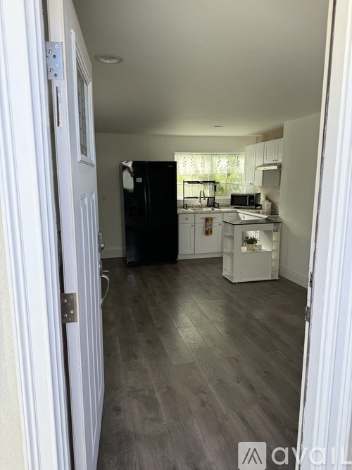 A kitchen with a black fridge and white cabinets.
