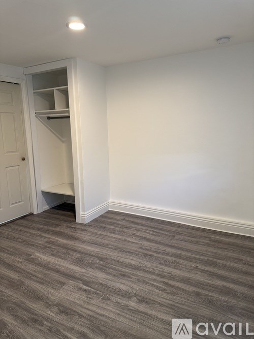 A room with a white door and a grey floor.