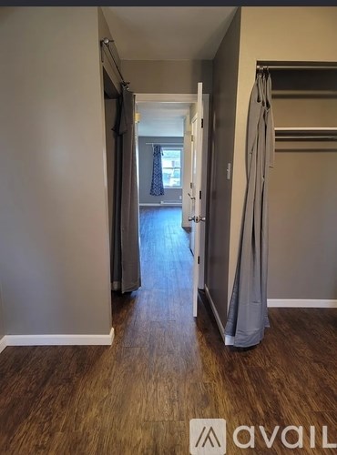 A hallway with a door open to a room with a window.