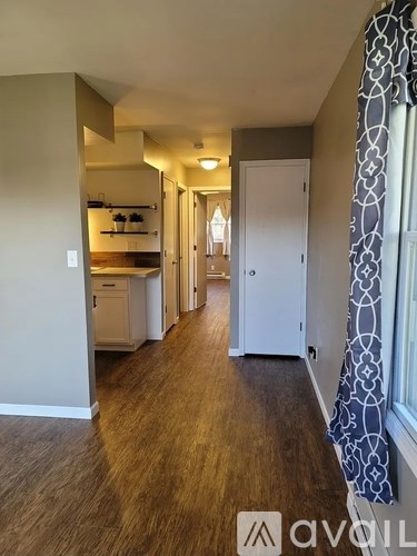 A hallway with a kitchen area visible through the doorway.
