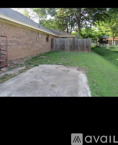 A backyard with a concrete pathway leading to a wooden fence.