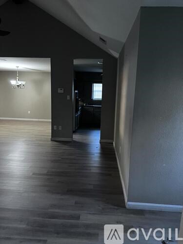 A hallway with wood floors and a chandelier.