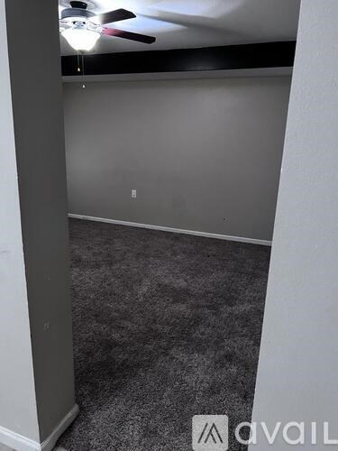 A room with grey carpet and a ceiling fan.