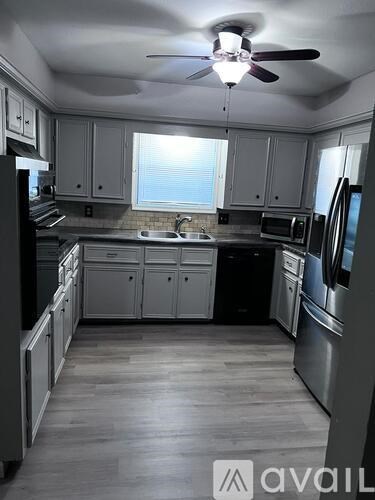 A kitchen with a fan on the ceiling and a window letting in light.