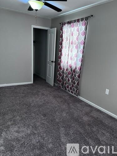 A room with a ceiling fan and a door leading to another room.