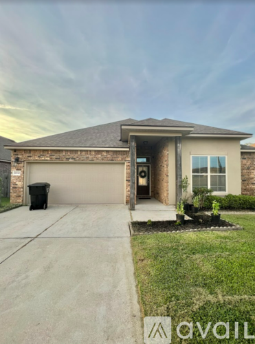 A house with a driveway and a trash can in front of it.