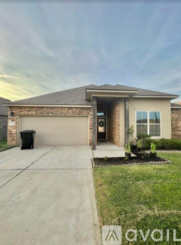 A house with a driveway and a trash can in front of it.