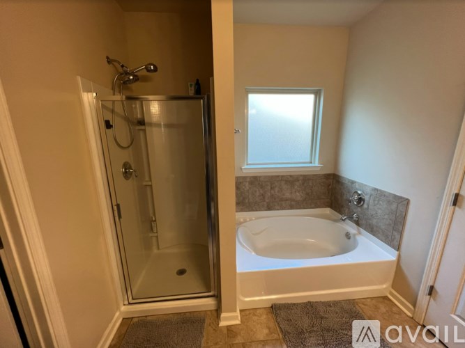 A bathroom with a glass shower door and a white bathtub.