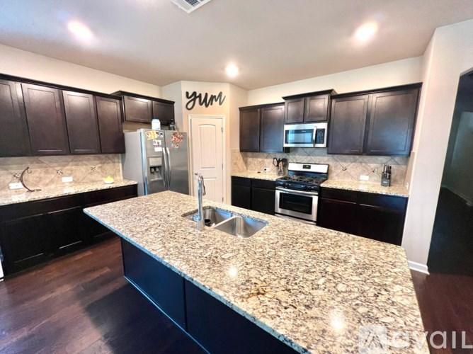 A kitchen with granite countertops and dark brown cabinets.