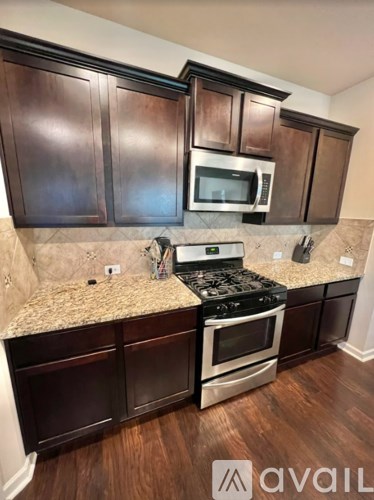 A kitchen with dark wood cabinets and a granite countertop.